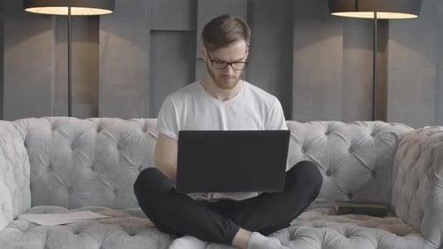 Portrait of Young Handsome Man Typing on Laptop Keyboard. Front View of Concentrated Caucasian