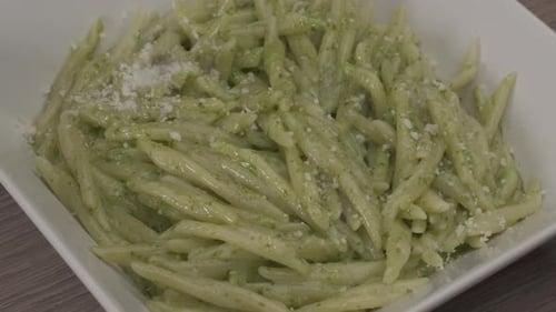 Pouring Cheese on Italian Pasta Al Pesto