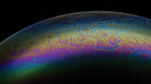Nahaufnahme der Seifenblase. Mehrfarbige Regenbogeniris wie bunter Gasplanet auf schwarzem Hintergrund