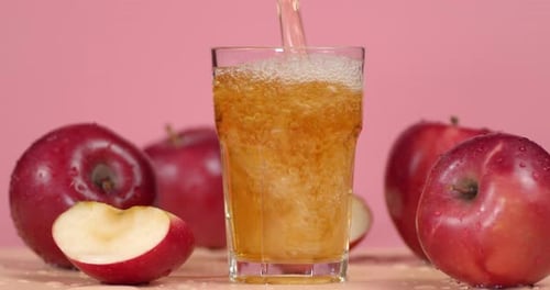 Refreshing Apple Juice Pouring into Glass with Apples