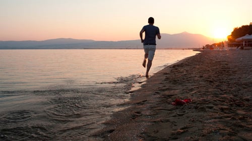 Man Running Along A Beach At Sunset