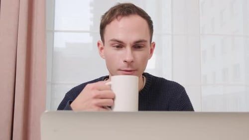 Man Drinking Coffee While Working on Computer