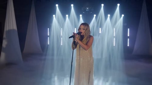 Woman Singing on Stage in Bright Lights