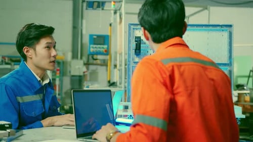 Male Asian engineer professional having a discussion standing by the machine in the factory