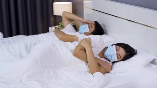 Couple Lying in Bed Wearing Surgical Masks