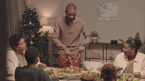 Family Gathered Around Table Carving Holiday Meal
