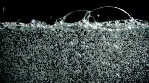 Kohlensäurehaltiges Wasser in das Glas gießen.