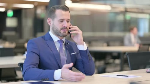 Professional Man Talking on Mobile Phone in Modern Office