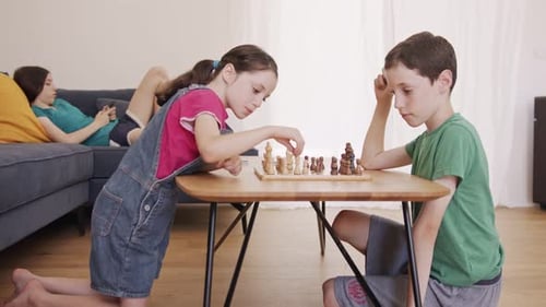 Young kids playing Chess on the living room table