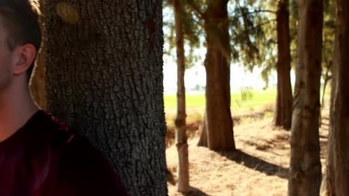 Thoughtful man leaning on tree trunk in olive farm