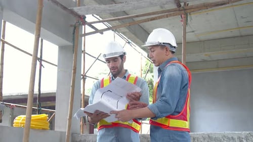 Construction Workers Review Blueprints On Site