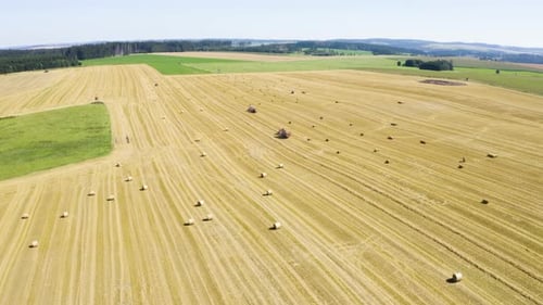Aerial Drone Shot a Field with Tractors and Hay Bales in a Rural Area on a Sunny Day