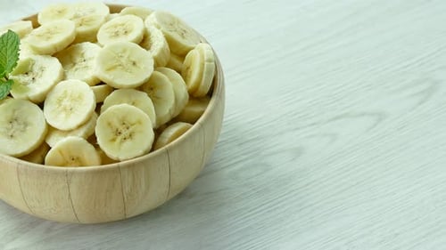 Wooden Bowl of Banana Slices Garnished with Mint