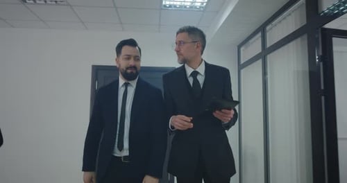 Businessmen Discussing Strategy on Tablet in Modern Office