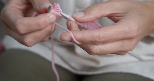 Woman's Hands Knitting with Pink Yarn Indoors