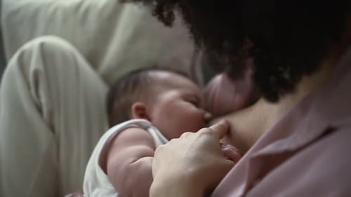Closeup View of Mother Breastfeeding Small Baby and Sitting on Sofa in Home Room Spbd