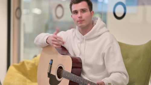 Man Playing Acoustic Guitar and Talking to Camera