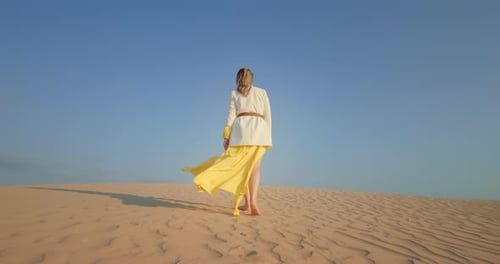 Female Traveler Walking Barefoot on Sand Dune in Desert