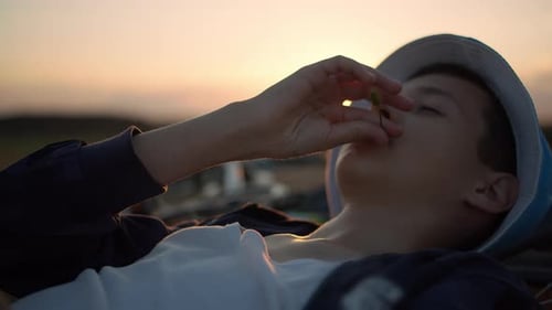 Young Boy Lying Down at Sunset with Flower