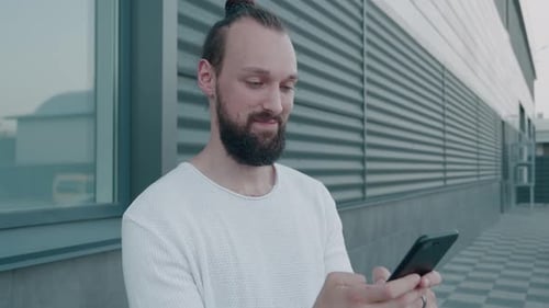 Man Using Phone Next to Modern Building