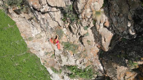 Woman Athlette Climbing on the High Rock in the Mountains