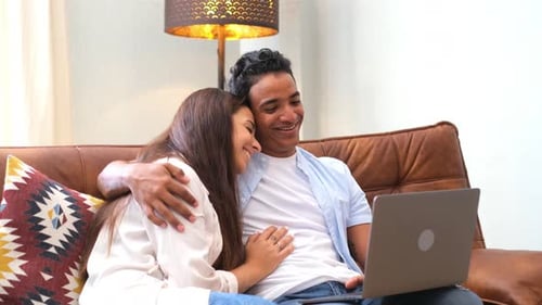 Smiling Couple Relaxing on Couch with Laptop