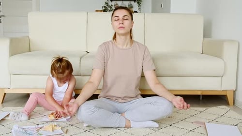 Mutter macht Yoga-Übungen zu Hause zum Stressabbau und entspannt sich, während ihr Kind kleine Tochter ablenkt