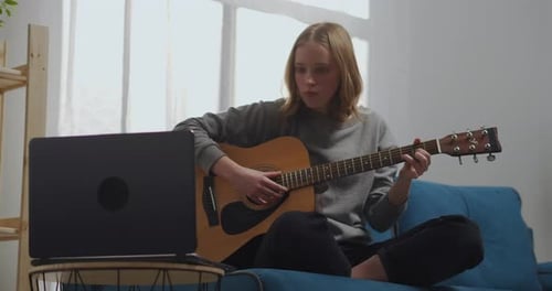 Girl Learning Guitar At Home Using Laptop