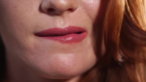 Nahaufnahme der Lippen einer Frau, die erotisch auf die Unterseite der Lippe beißt