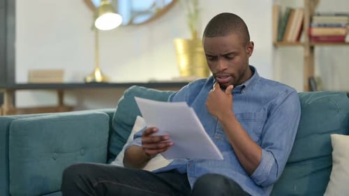 Adult Reading Documents at Home on Couch