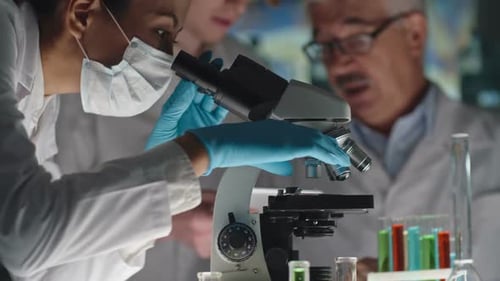 Scientists Work Together Using Microscope in Lab