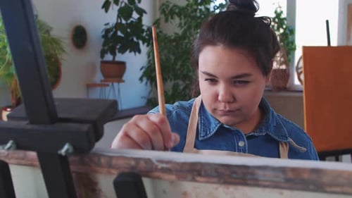Young Artist Painting on Canvas in Bright Studio