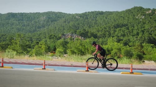 Woman Rides Bicycle Along Paved Road, Daytime
