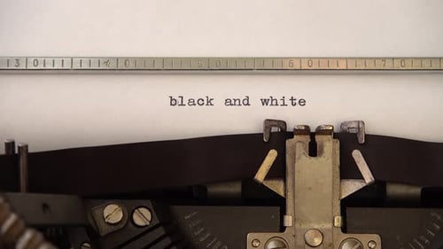 Typing phrase black and white on retro typewriter. Close up.