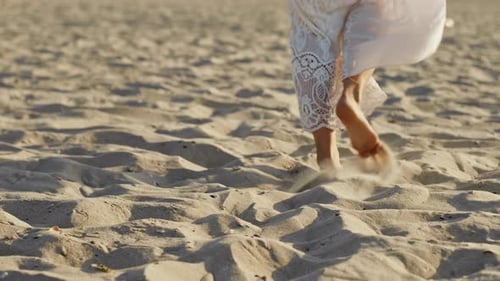 Legs of Girl Wearing White Long Dress Walking Barefoot Sand on Sea Beach or Desert. Slow Motion