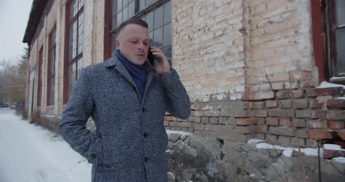 Man Talking on Smartphone on Snowy Urban Street