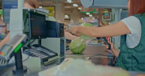 Female Customer Lays Out Products at the Supermarket Checkout