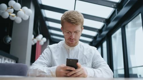 Male Professional Holding Modern Smartphone Texting Message in Office