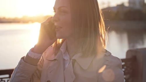 Woman Talking on Phone During Sunset By River