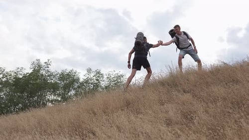 Men Hiking Up Grassy Hillside Together