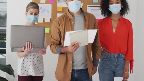 Office colleagues wearing face mask standing in office