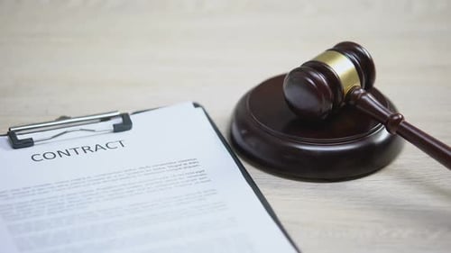 Documento de contrato sobre la mesa, golpe de martillo en bloque de sonido, asesoramiento legal, acuerdo