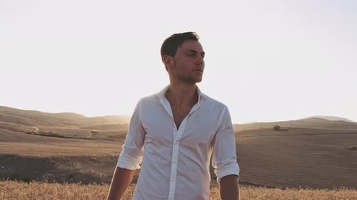 Homem com camisa abotoada olhando de soslaio enquanto caminhava em prados abertos