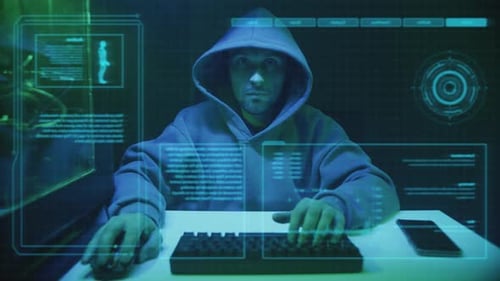 Hooded Hacker Typing at Computer in Dark Room