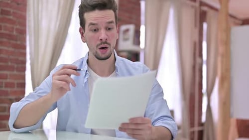 Man Reading Document with Surprised Expression Indoors