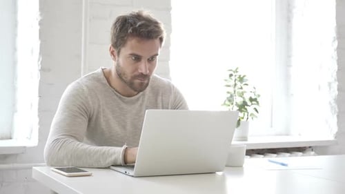 Man Celebrating Success at Computer in Bright Office