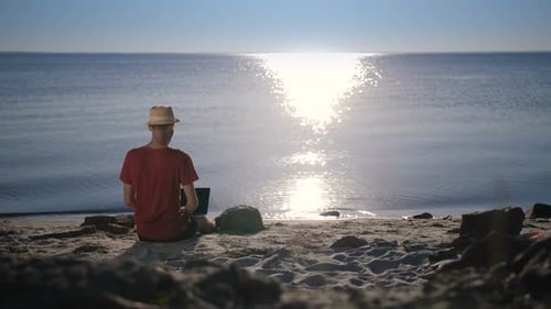 Adult Working Remotely on Beach with Laptop