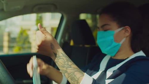 Woman in Car Sanitizing Hands with Blue Mask