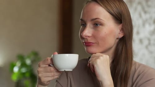 Portrait of a Joyful Young Woman Enjoying a Cup of Coffee at Home