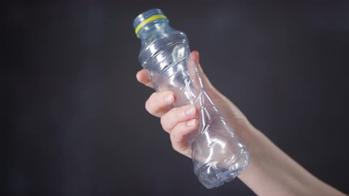 Hand Crushing a Plastic Bottle to Recycle